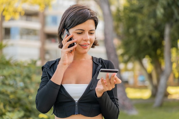 Foto joven bonita búlgara al aire libre comprando con el móvil con tarjeta de crédito