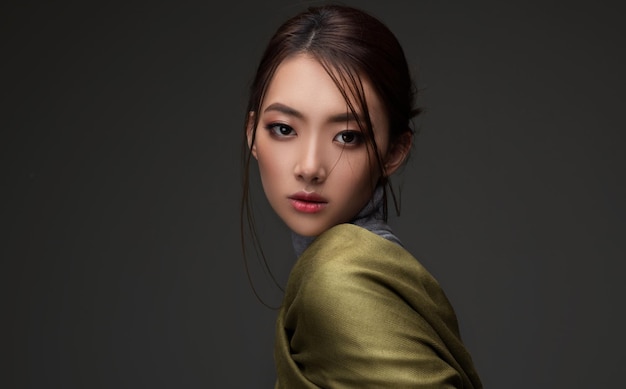 Joven y bonita modelo china vestida con ropa de lana Retrato sobre fondo oscuro Belleza asiática