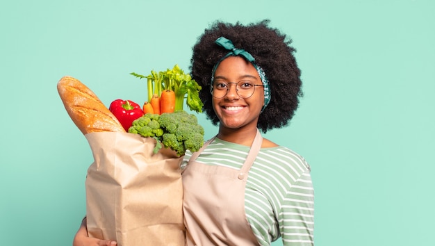 Joven bonita a mujer afro con una bolsa de papel de verduras