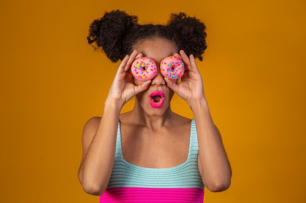 Joven bonita a mujer afro con una dona