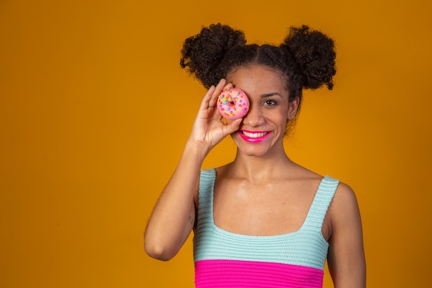 Joven bonita a mujer afro con una dona