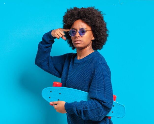 Joven bonita a mujer afro con una patineta