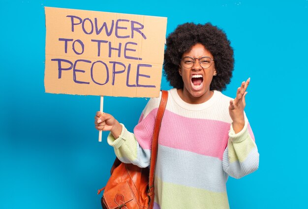 Joven bonita a mujer afro protestando con un poder a la pancarta de la gente