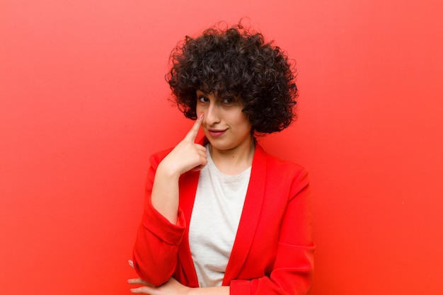 Joven y bonita mujer afro que te vigila, sin confiar, mirando y permaneciendo alerta y vigilante