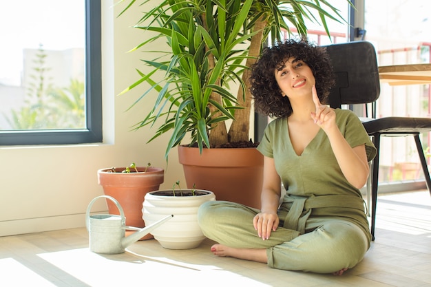 Joven bonita a mujer árabe en casa, con una regadera y plantas