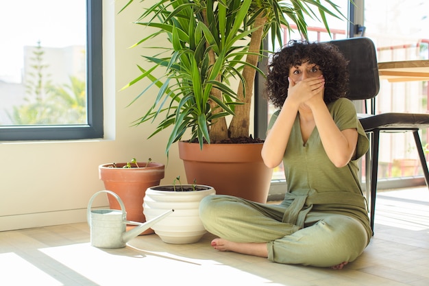 Joven bonita a mujer árabe en casa, con una regadera y plantas