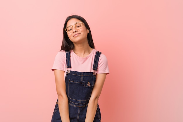 Joven bonita mujer árabe vestida con un peto de jeans que sueña con lograr objetivos y propósitos