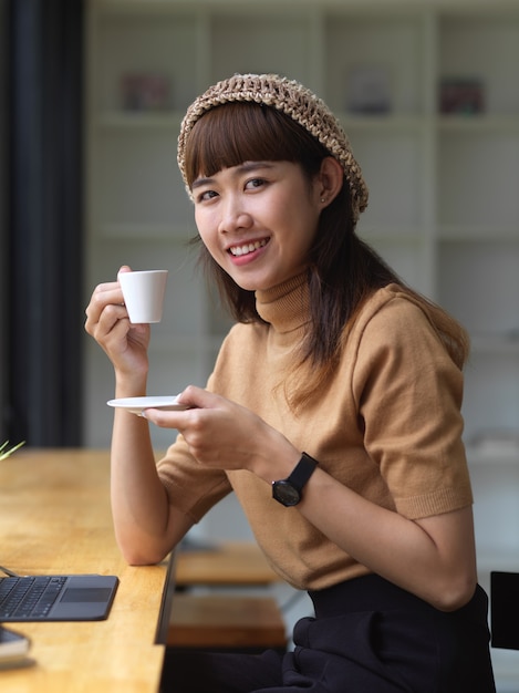 Joven bonita a mujer asiática sosteniendo una taza de café