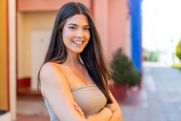 Foto joven y bonita mujer brasileña al aire libre con los brazos cruzados y mirando hacia adelante