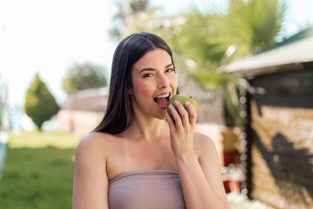 Joven y bonita mujer brasileña al aire libre comiendo una manzana