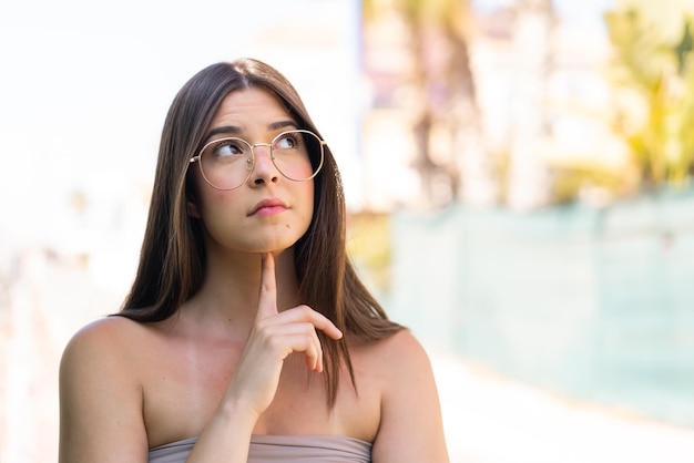 Joven y bonita mujer brasileña al aire libre con gafas y mirando hacia arriba