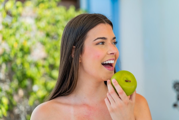 Joven y bonita mujer brasileña al aire libre sosteniendo una manzana