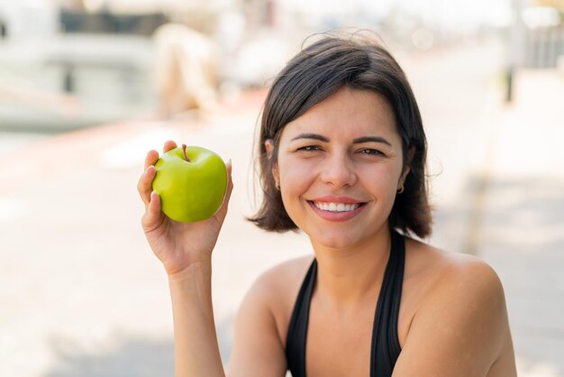 Joven y bonita mujer búlgara al aire libre con una manzana