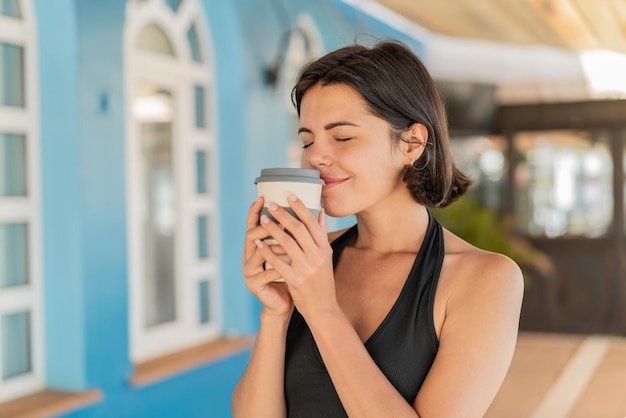 Joven y bonita mujer búlgara al aire libre sosteniendo un café para llevar