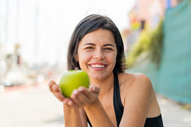 Foto joven y bonita mujer búlgara al aire libre sosteniendo una manzana