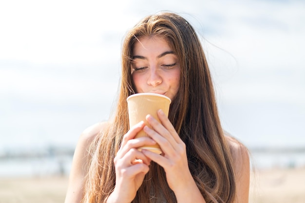 Joven y bonita mujer caucásica con un café para llevar