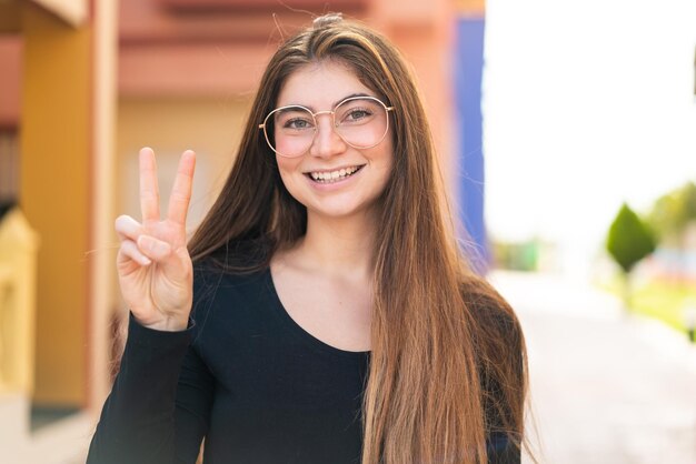 Joven y bonita mujer caucásica con gafas y haciendo el signo OK