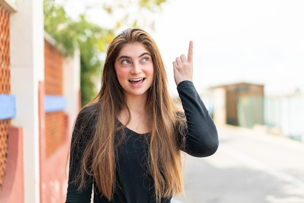 Joven y bonita mujer caucásica con la intención de darse cuenta de la solución mientras levanta un dedo