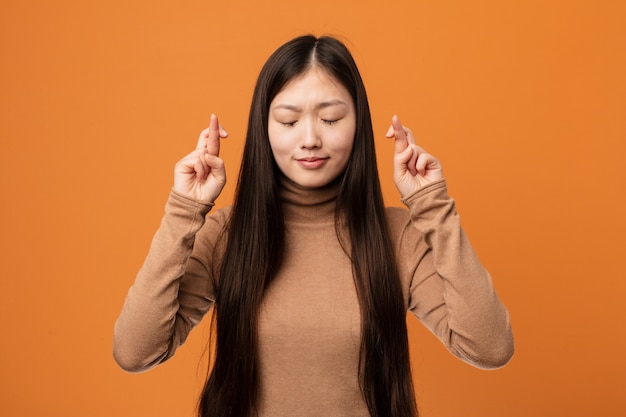 Joven bonita mujer china cruzando los dedos para tener suerte