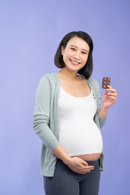 Joven bonita a mujer embarazada asiática comiendo chocolate