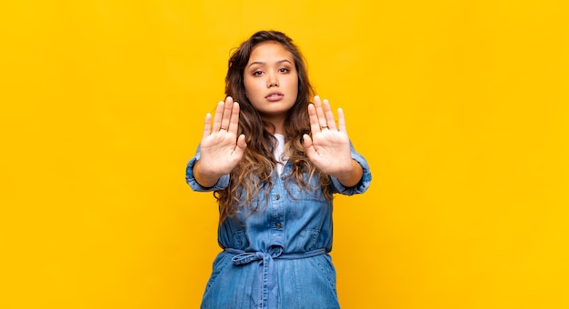 Joven bonita a mujer hispana contra la pared aislada