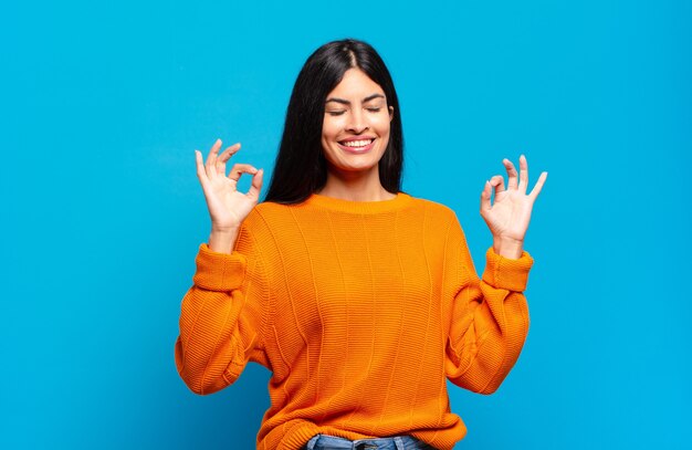 Joven bonita a mujer hispana que parece concentrada y meditando, sintiéndose satisfecha y relajada, pensando o haciendo una elección