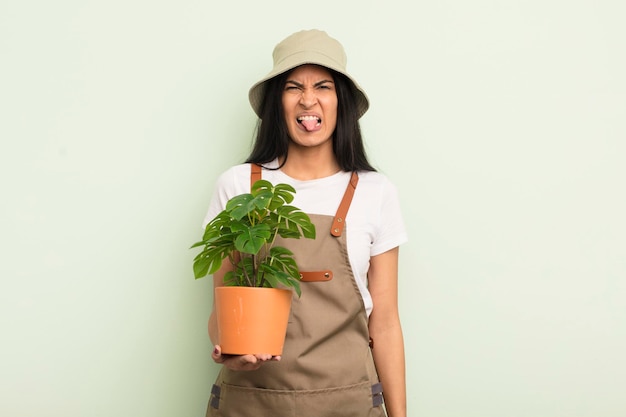 joven y bonita mujer hispana que se siente disgustada e irritada y saca la lengua del concepto de agricultor o jardinero