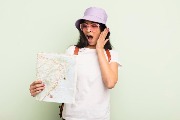 Joven bonita mujer hispana que se siente feliz emocionada y sorprendida turista y concepto de mapa