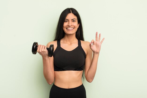 joven y bonita mujer hispana que se siente feliz, mostrando aprobación con un gesto bien. concepto de fitness