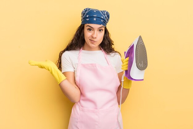 joven y bonita mujer hispana que se siente perpleja, confundida y dudando. concepto de plancha y ropa