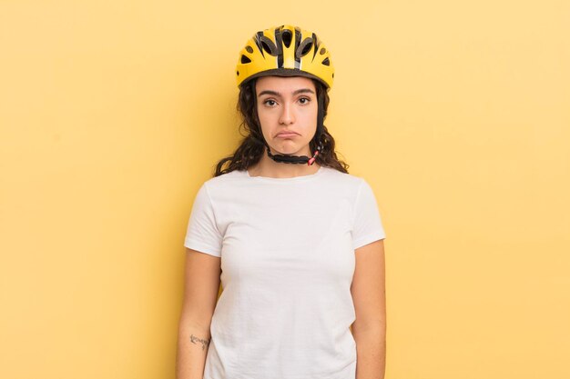 Joven bonita mujer hispana que se siente triste y quejumbrosa con una mirada infeliz y llorando. concepto de bicicleta