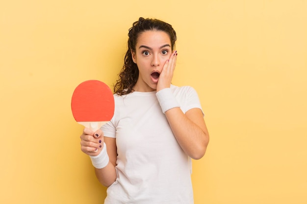 Joven bonita mujer hispana sintiéndose sorprendida y asustada. concepto de ping pong