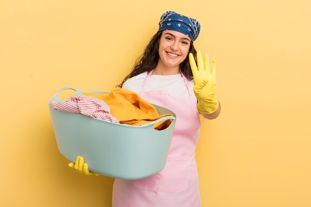 Joven bonita mujer hispana sonriendo y luciendo amigable mostrando el concepto número cuatro de lavado y ropa