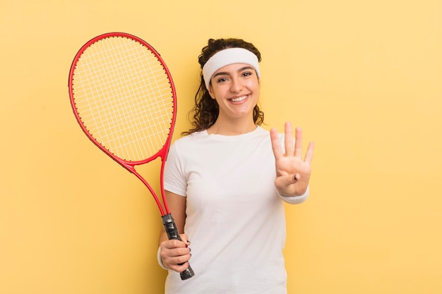Joven bonita mujer hispana sonriendo y luciendo amigable mostrando el concepto de tenis número cuatro
