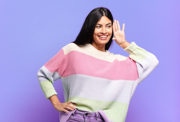 Joven bonita a mujer hispana sonriendo, mirando con curiosidad hacia el lado