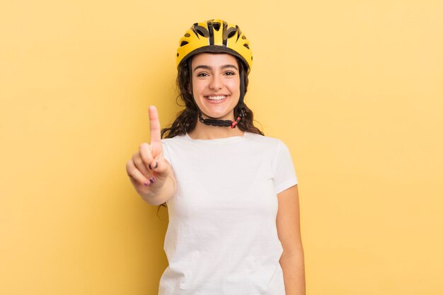 Joven bonita mujer hispana sonriendo con orgullo y confianza haciendo el concepto de bicicleta número uno