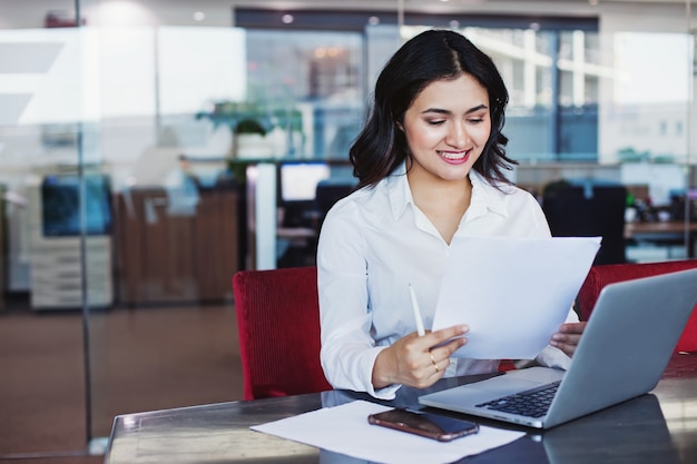 Foto joven bonita a mujer india sosteniendo un documento y sentado