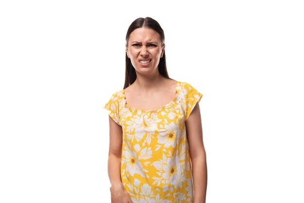 Una joven y bonita mujer morena vestida con una camiseta amarilla de verano hizo una cara