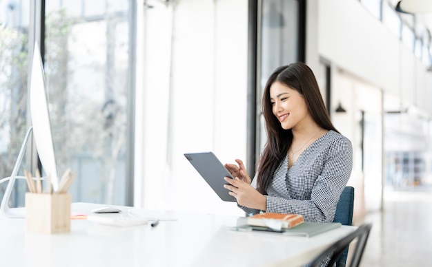 Joven y bonita mujer de negocios usando una tableta digital sentada en la oficina