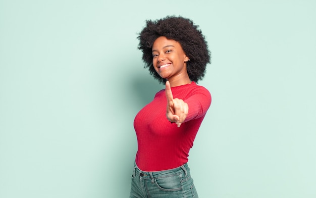 Joven bonita a mujer negra mostrando un dedo, el número uno