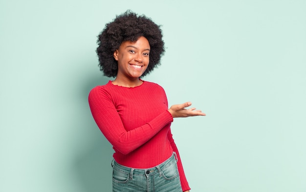 Joven bonita a mujer negra mostrando o presentando algo en el espacio de copia