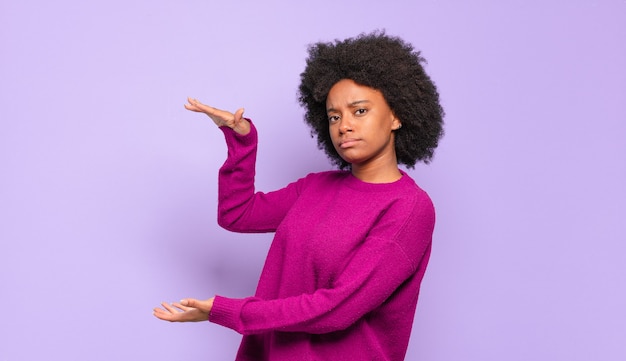 Joven bonita a mujer negra presentando o mostrando un producto