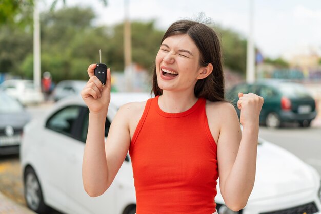 Joven y bonita mujer ucraniana con llaves de coche al aire libre celebrando una victoria