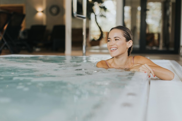 Una joven bonita relajándose en la piscina de burbujas cubierta