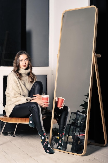 Foto una joven bonita está sentada en una silla con pantalones de cuero