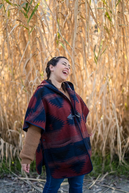 una joven bonita sonriendo y posando frente a algunas ramas en el campo