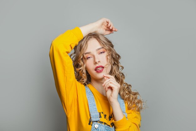 Una joven bonita con una sudadera amarilla sobre un fondo gris