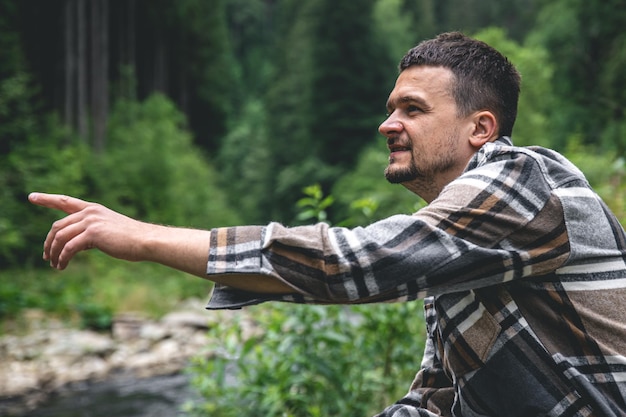 Un joven en el bosque cerca del río disfruta de la naturaleza un alto