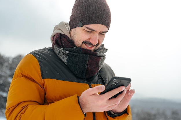 Un joven en un bosque nevado de invierno usando un teléfono móvil