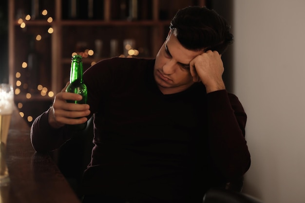 Joven con botella de cerveza en el bar Problema de alcoholismo